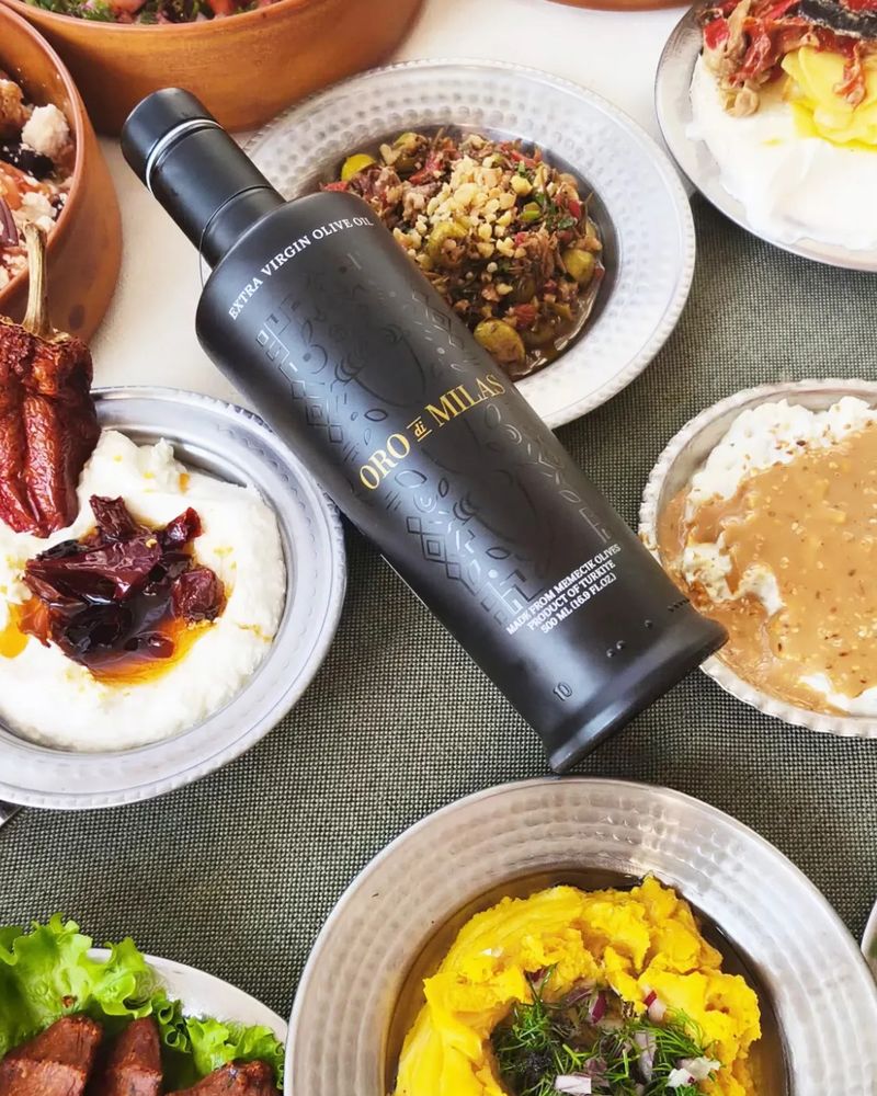 A bottle of Oro di Milas Reserve extra virgin olive oil among plates of meze: strained yoghurt with dried peppers, a bulgur and walnut salad, split pea purée with dill